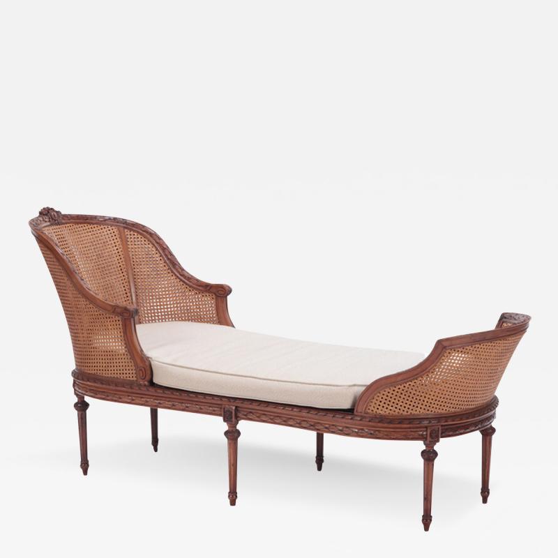 A French carved walnut chaise lounge in the Louis XVI style Circa 1900 