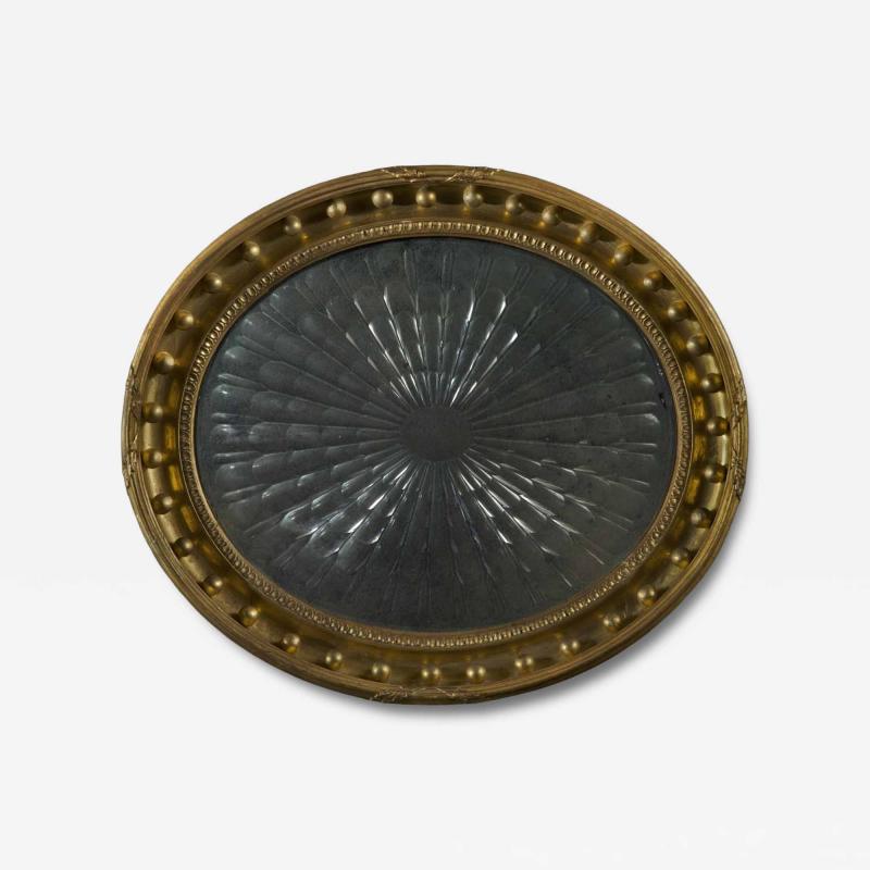 A Regency oval wall mirror cum light reflector with decorative scalloped design