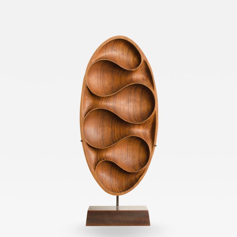 A carved wood almond shaped sculpture and base