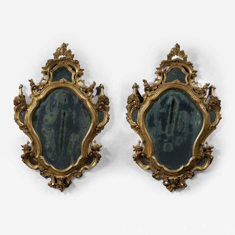 A fine pair of barocchetto escutcheon shaped giltwood mirrors cum girandoles