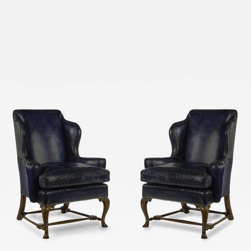 A pair of walnut Georgian style leather wing armchairs