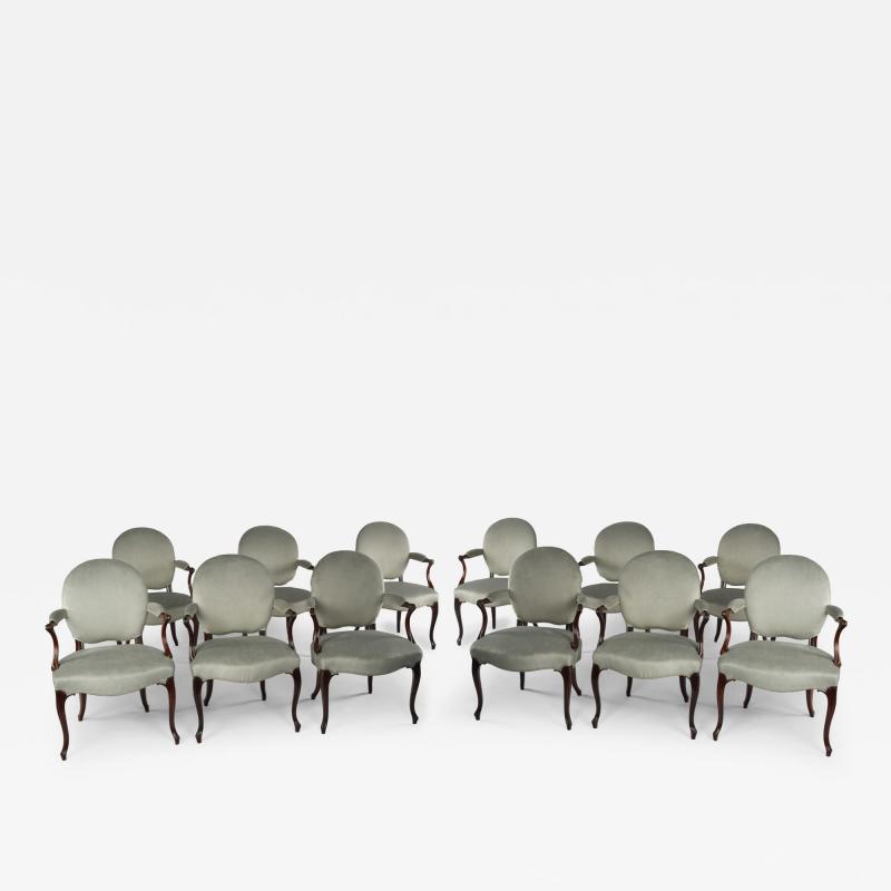 A rare set of twelve George III mahogany open arm chairs in the French Hepplewhi