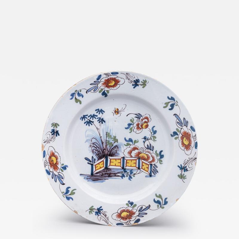 DELFT CHARGER DECORATED WITH FLOWERS AND A FENCE