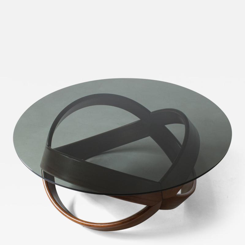 Low table with curved wooden base and smoked glass top 