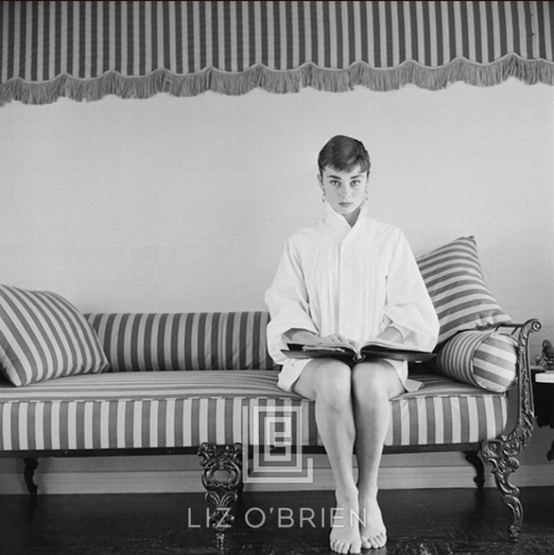 Mark Shaw Audrey Hepburn on Striped Sofa Faces Forward with Book Open 1954