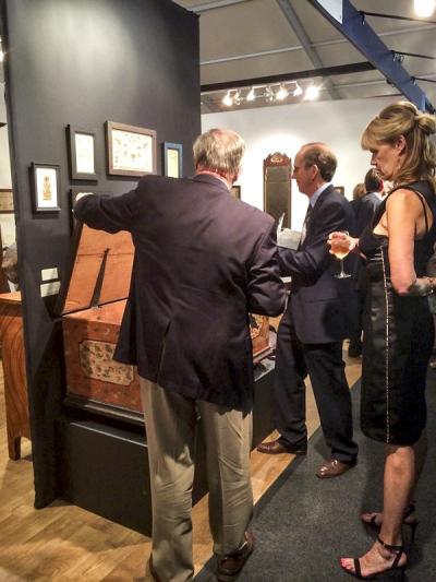 Examining a painted dower chest in the booth of Philip Bradley (center).