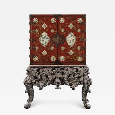 A RED LACQUERED CABINET WITH SHAPED PANELS