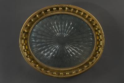 A Regency oval wall mirror cum light reflector with decorative scalloped design
