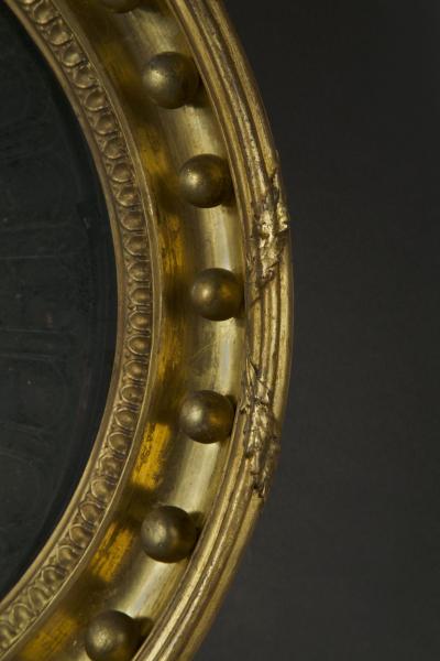 A Regency oval wall mirror cum light reflector with decorative scalloped design
