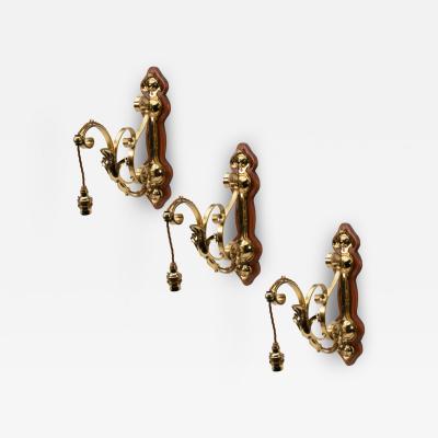 A Set of Three Arts Crafts Brass Wall Lights with Walnut Backplates