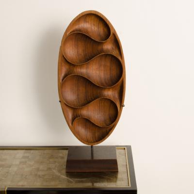 A carved wood almond shaped sculpture and base