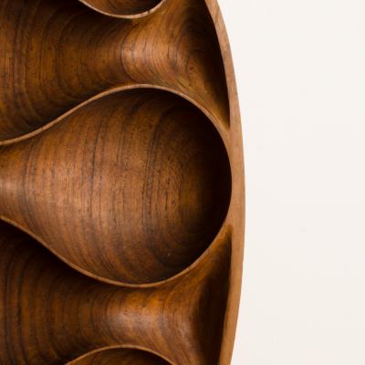 A carved wood almond shaped sculpture and base