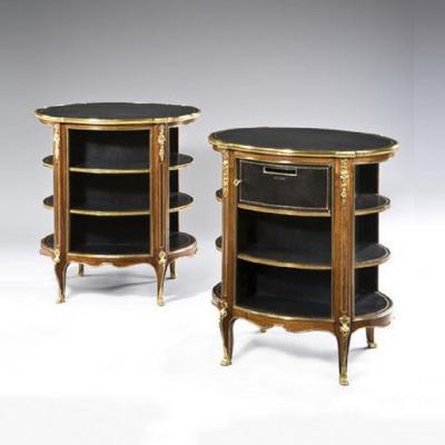 A pair of open library bookcases are inset with oval black leather tops