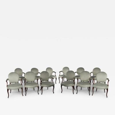 A rare set of twelve George III mahogany open arm chairs in the French Hepplewhi