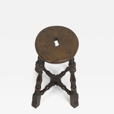 An Aesthetic Movement Elm Stool with a S Handle a Wild Grain to the Seat
