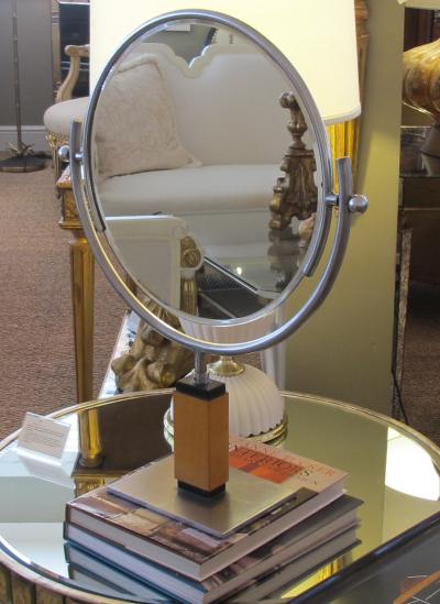 An American art deco steel dressing mirror raised on a maplewood base