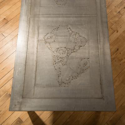 An artist designed metal clad silver color coffee table with holes in top