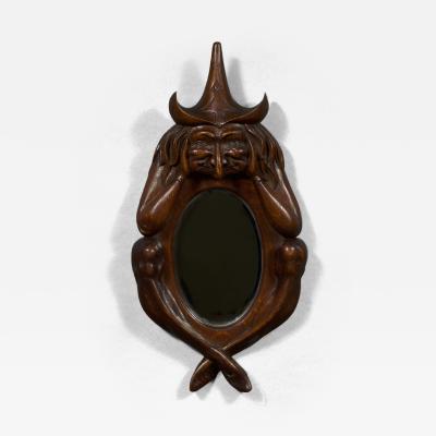 An oval arts and crafts period carved oak scrying mirror in the form of a witch
