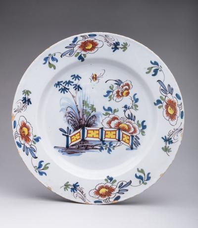 DELFT CHARGER DECORATED WITH FLOWERS AND A FENCE
