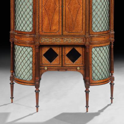 FINE REGENCY AMBOYNA AND EBONY INLAID GILT BRONZE MOUNTED SHAPED CABINET