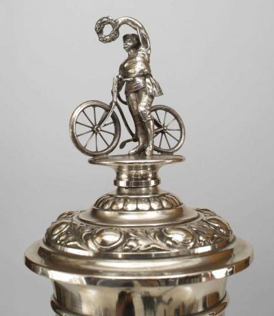 German silver plate chalice with floral relief and bicycle rider finial on lid
