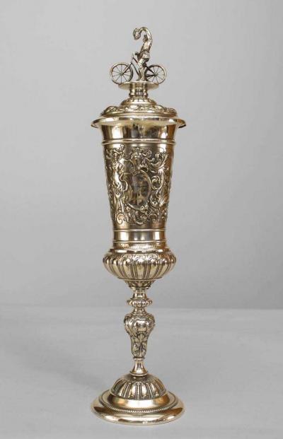 German silver plate chalice with floral relief and bicycle rider finial on lid