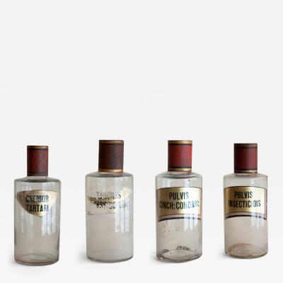 SET OF FOUR HAND BLOWN GLASS APOTHECARY BOTTLES WITH GILT AND RED TOPS